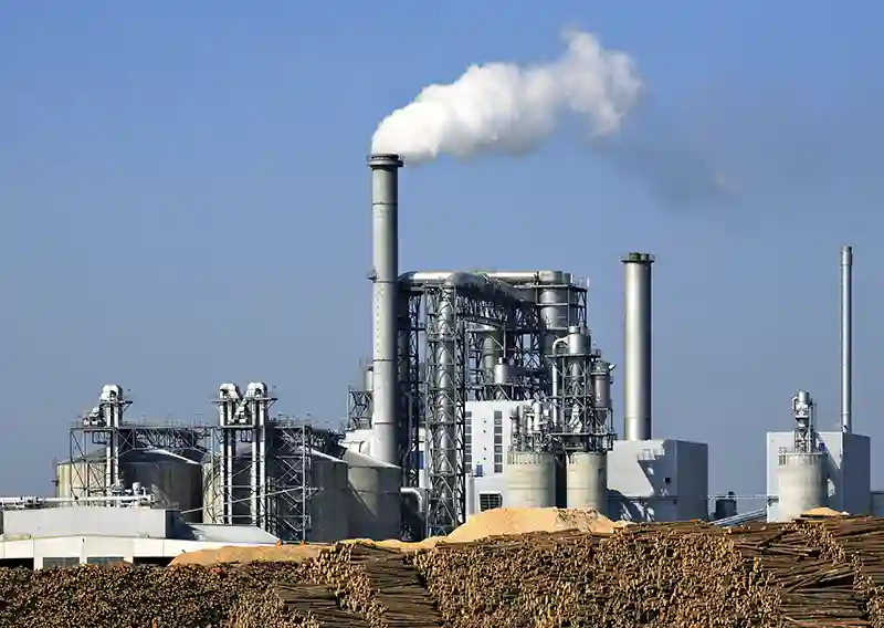 Usine papetière avec émissions industrielles illustrant les enjeux de performance et de carbone dans l’industrie