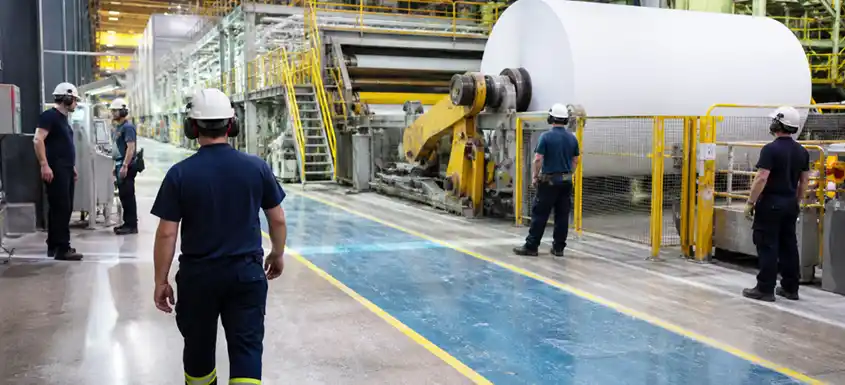 Opérateurs surveillant une machine à papier dans une usine de pâtes et papiers